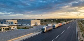 Photographie éditoriale de haute qualité, prise par drone au crépuscule (heure dorée). La composition en plongée montre un poste frontière tunisien modernisé et sécurisé, symbolisant la volonté de transformation en hub économique.