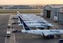 Vue aérienne au lever du soleil sur le tarmac de l'aéroport Tunis-Carthage. On y distingue clairement une rangée d'avions de la compagnie privée Nouvelair (livrée blanche et bleue, incluant le nouvel A320neo) alignés parallèlement à une rangée d'appareils Tunisair (livrée blanche avec la gazelle rouge).